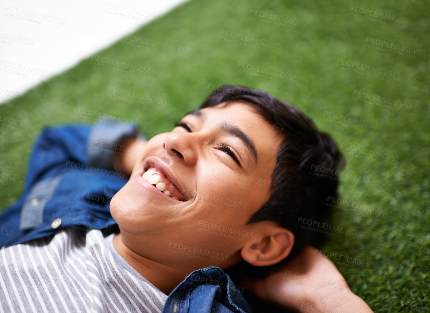 Buy stock photo Boy, relax and lying on grass in backyard, resting and enjoying summer and nature outdoor. Children, smile and sunshine after school in park, adorable kid and joyful in garden or lawn with happiness