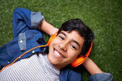 Buy stock photo Boy child, grass and lying with headphones in portrait for music, streaming and online audio with happiness. Male kid, happiness and listening to sound, internet radio or podcast on lawn in garden