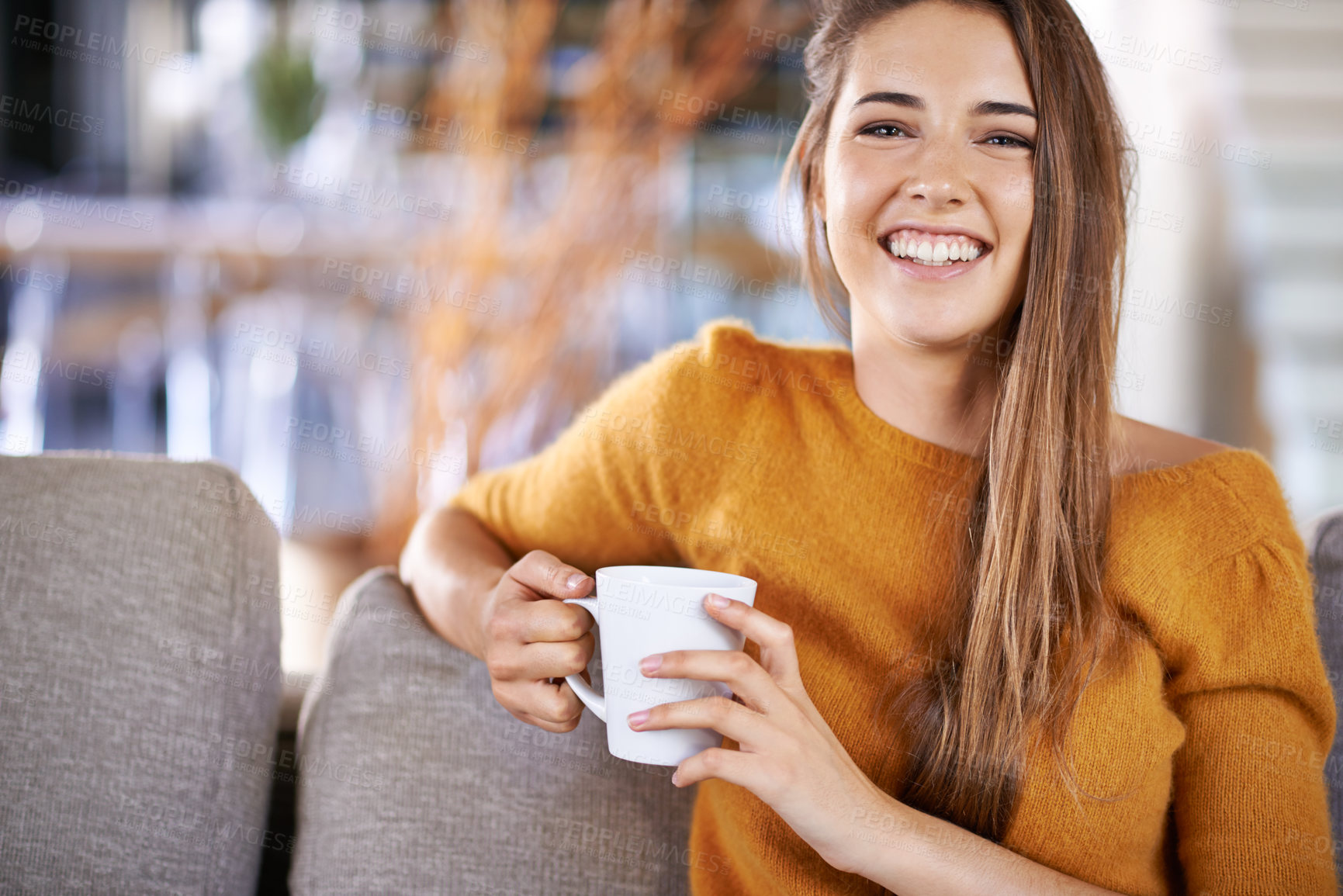 Buy stock photo Cropped image of a pretty young female drinking coffee while sitting on the sofa