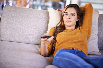 Buy stock photo Cropped shot of an attractive young woman changing TV channels with the remote