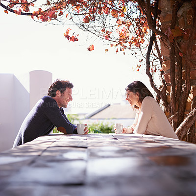 Buy stock photo A couple seated at a wooden table beneath the autumn leaves