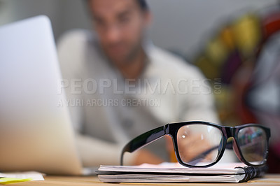 Buy stock photo Shot of a pair of glasses lying on a notepad on the desk of a businessman