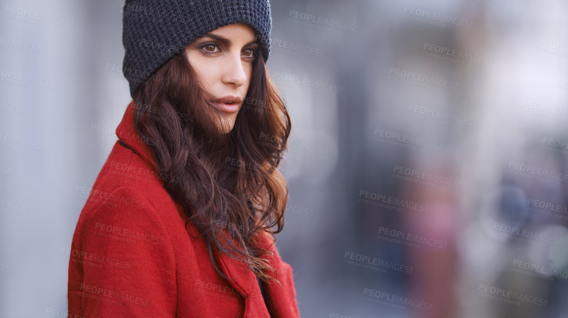 Buy stock photo Shot of a beautiful young woman in winter clothing standing in an urban setting