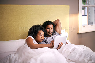 Buy stock photo Portrait of a young couple lying in bed using a laptop