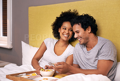 Buy stock photo Couple, smile and bedroom for breakfast on tray for wakeup, morning and food for eat, rest and relax. Diverse and young people and laugh with happiness for bonding with fruit and bowl for joy  