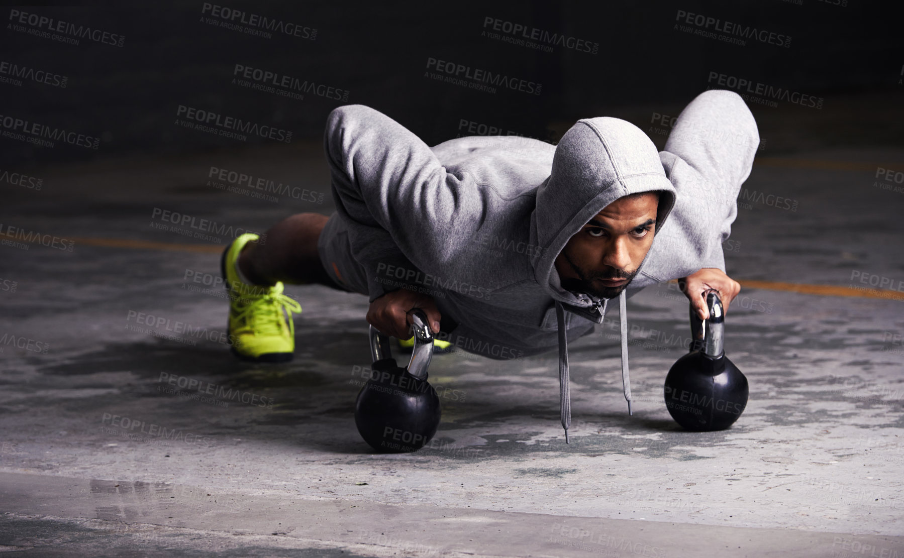 Buy stock photo Shot of a young man doing push-ups with kettle bell weights