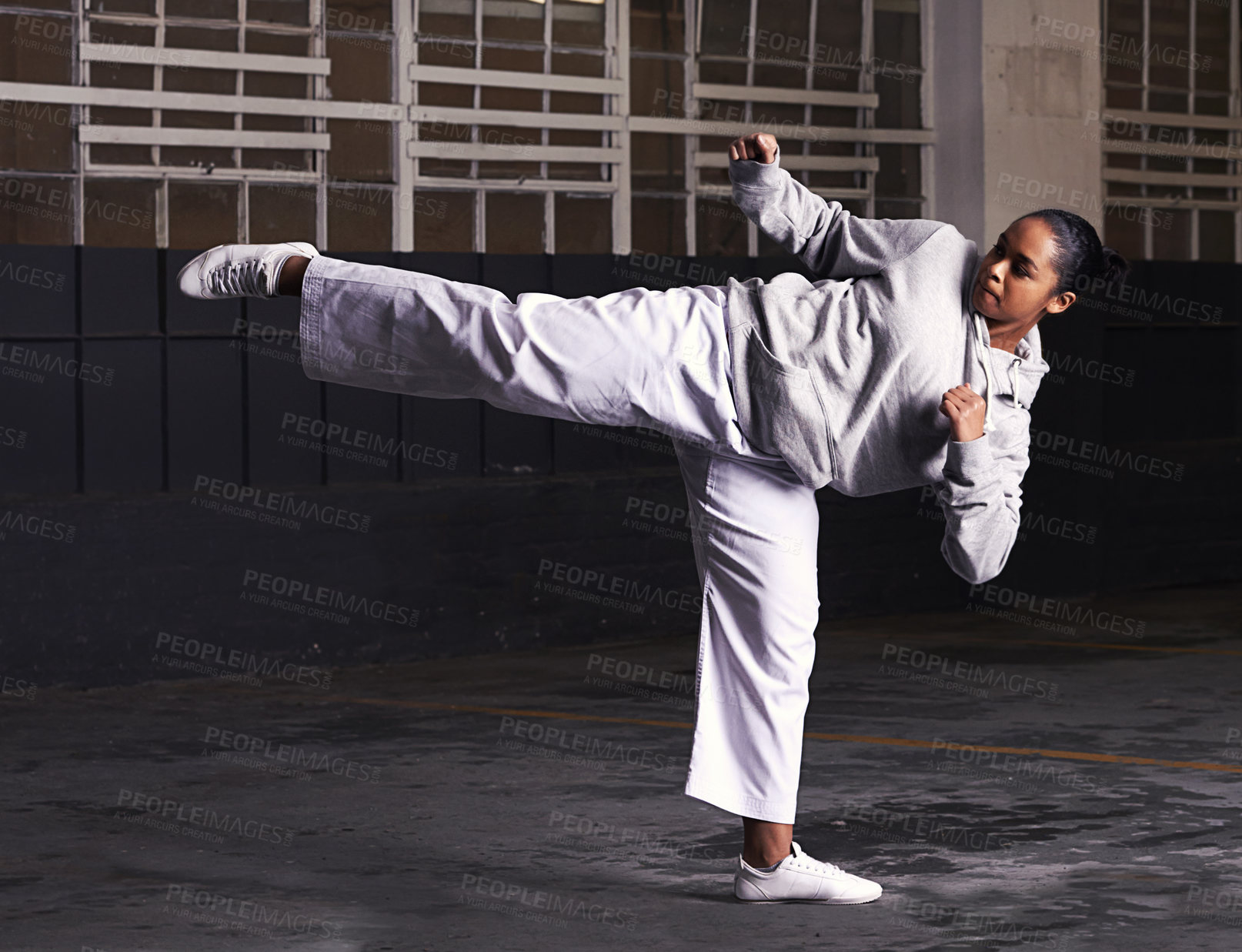 Buy stock photo Martial arts, woman and fitness in building for training with kick, exercise and practice for competition at night. Karate, athlete and workout for self defense, discipline and technique in warehouse