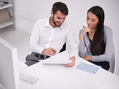 Buy stock photo Shot of two young business colleagues discussing documents in the office