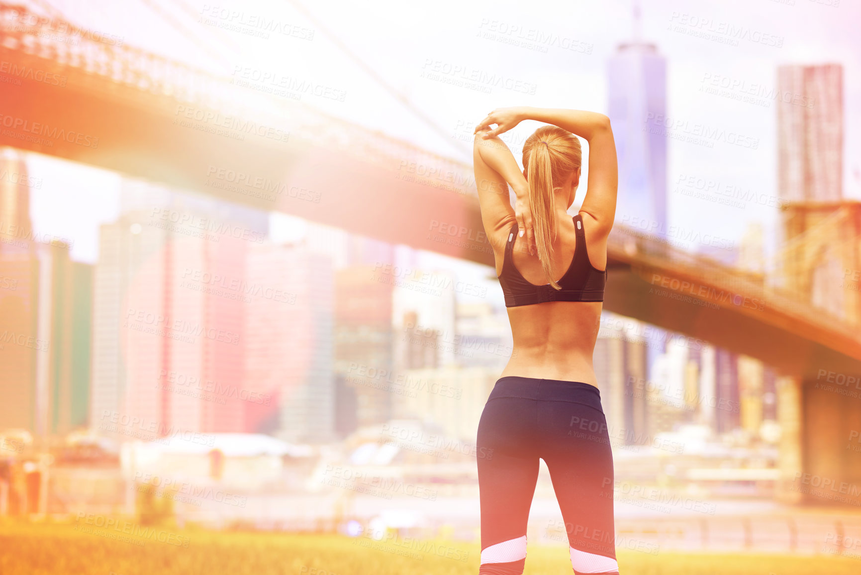 Buy stock photo Rear view shot of a beautiful woman stretching  before her run with the city in the background