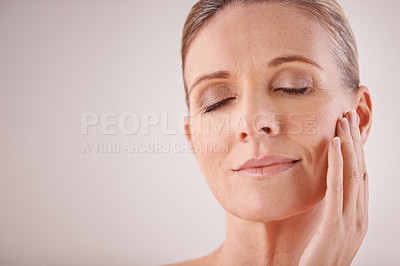 Buy stock photo Cropped studio shot of a beautiful mature woman touching her face