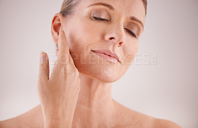 Buy stock photo Face, beauty and skincare with an old woman in studio on a gray background for natural antiaging treatment. Facial, skin care and wellness with an attractive senior female model touching her cheek