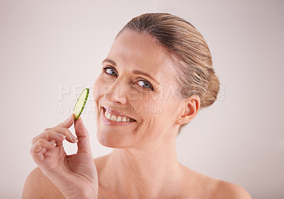 Buy stock photo Mature woman, portrait and cucumber for skincare in studio with healthy skin, organic detox and facial wellness. Model, person and happy face with fruit for anti aging treatment on white background