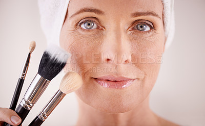 Buy stock photo Portrait, mature woman and makeup with brushes, cosmetics and dermatology on grey studio background. Face, person and model with product and tool with wellness and skincare with treatment or grooming