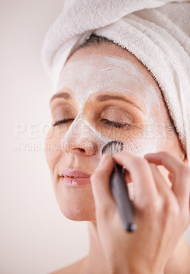 Buy stock photo Hand, mature woman and mask with brush in studio for skincare or anti aging on self care, wellness and fresh skin. Closeup, female person and glow with smile or happy for facial and beauty for luxury
