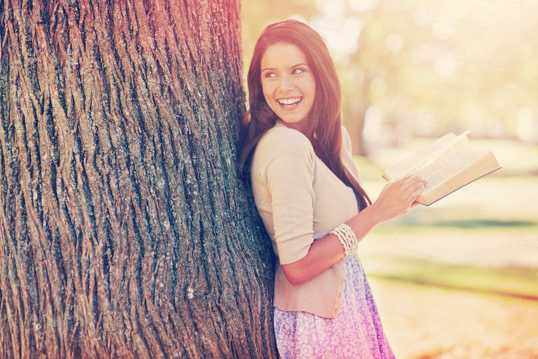 Buy stock photo Tree trunk, portrait and woman with smile for novel, book and fiction in nature to relax in park. Adult, girl and female person with confidence for knowledge, happy and joy for reading in summer