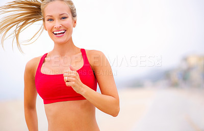 Buy stock photo Shot of a young woman jogging near the beach