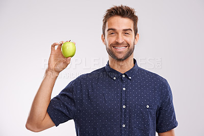 Buy stock photo Portrait of a handsome young man holding an apple and smiing