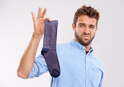 Buy stock photo Studio shot of a handsome young man holding an unpleasant smelling sock against a gray background