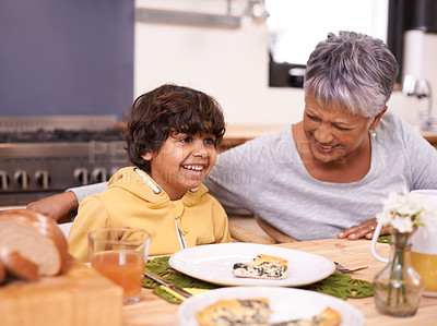 Buy stock photo A cute little boy eating a meal with his grandmother at home