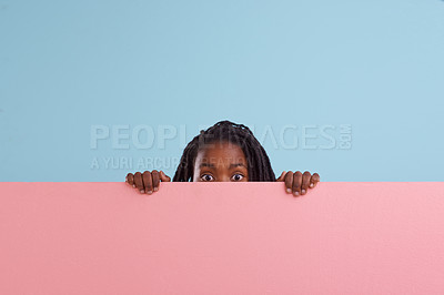 Buy stock photo Studio portrait of a young boy peering from behind a blank signboard