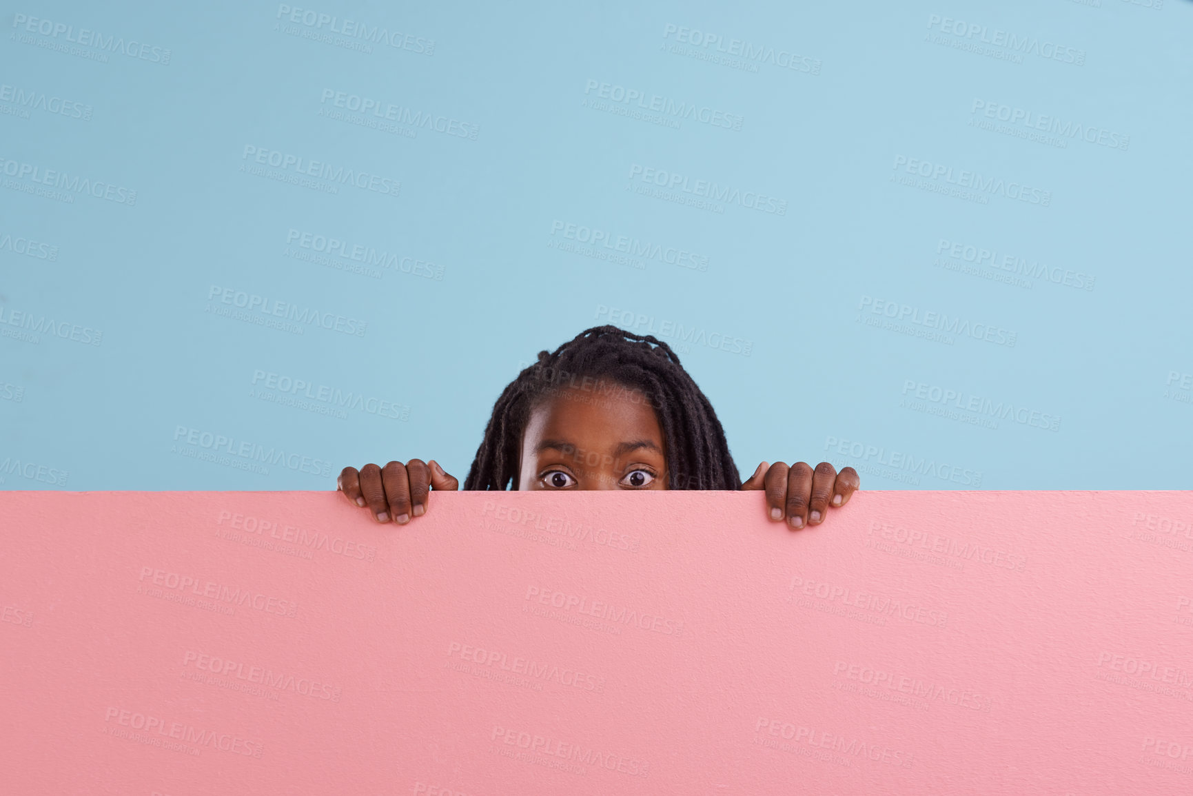 Buy stock photo Studio portrait of a young boy peering from behind a blank signboard