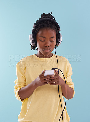 Buy stock photo Phone, music and black boy with headphones in studio for internet, playlist or search on blue background. Smartphone, radio and teen model with app for podcast, streaming or sign up subscription