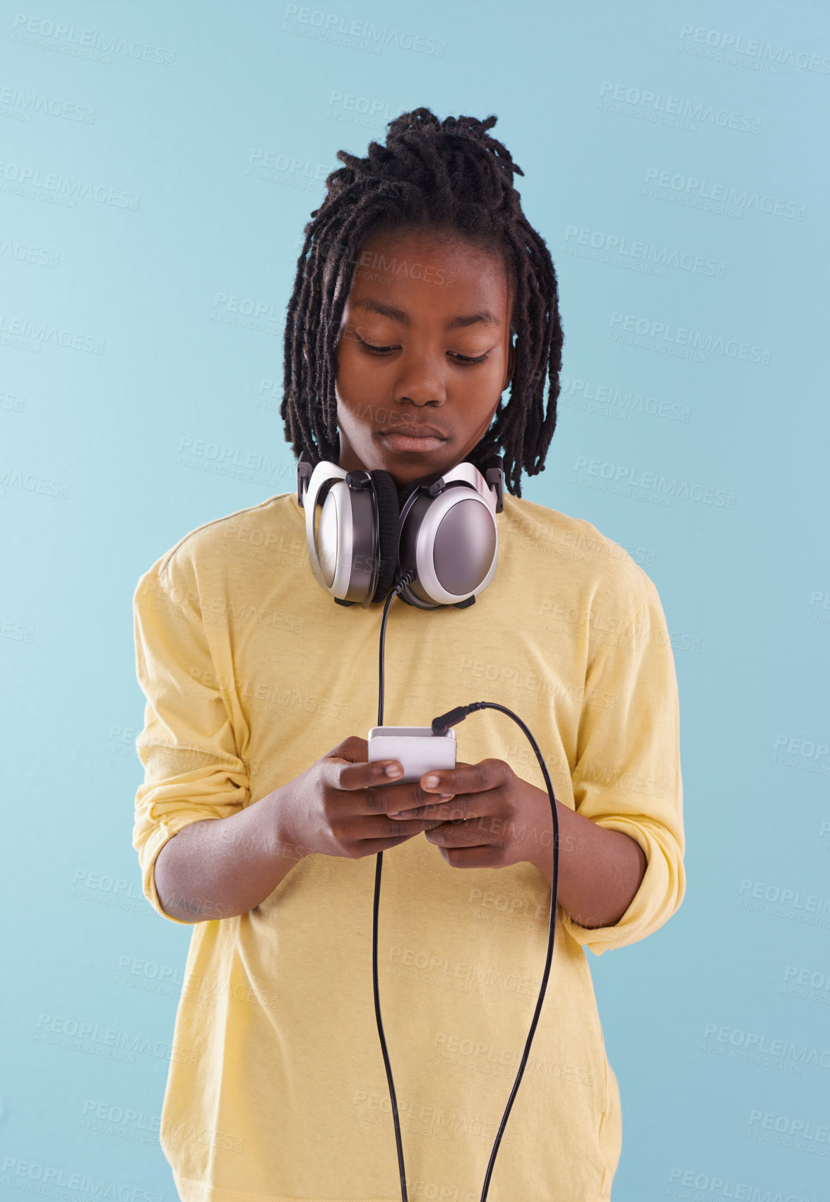 Buy stock photo Music, headphones and black kid in studio for internet, playlist or track search on blue background. Smartphone, radio and African teen boy with app for podcast, streaming or sign up subscription