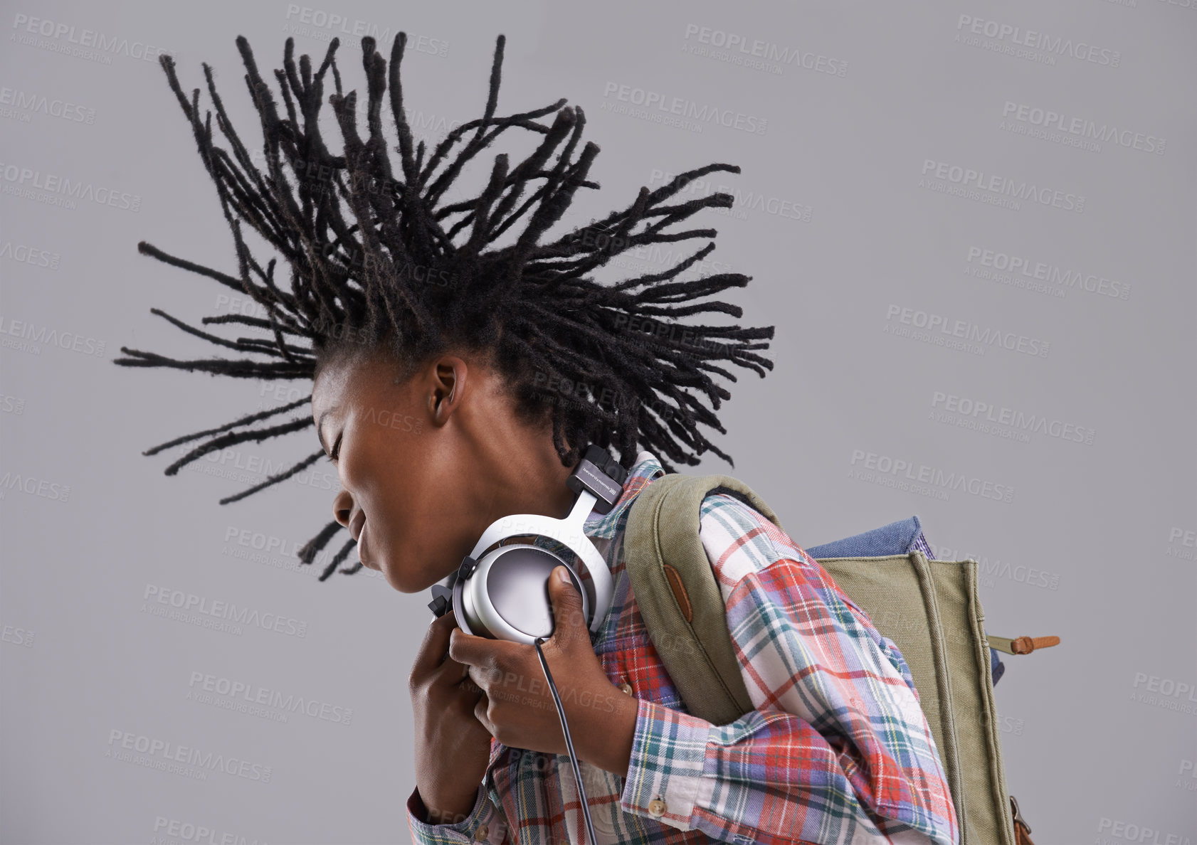 Buy stock photo Black child, music and hair flip of a teenager with hip hop and rap audio in a studio. Excited, backpack and student with headphones for radio before school with a happy smile and grey background