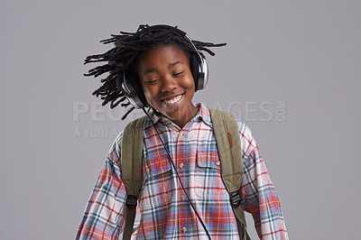 Buy stock photo Black man, music and smile of a teenager with hip hop and rap audio in a studio. Relax, backpack and student with headphones streaming a radio song before school with a happy kid and grey background