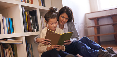 Buy stock photo A mother and daughter reading a book together at home