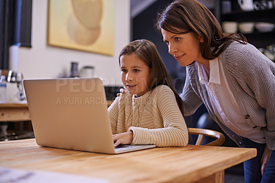 Buy stock photo Mom, child and learning with laptop for support, care or browsing in the kitchen at home. Mother, daughter or kid typing on computer for social media, reading or helping girl on project or homework