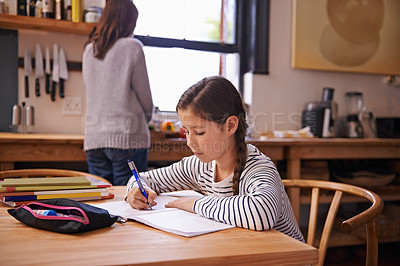 Buy stock photo A busy young girl doing her homework at the kitchen table