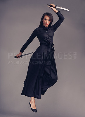 Buy stock photo Ninja, blade and woman warrior in a studio jumping for a martial arts or assassin fighter skill. Fantasy, cosplay and portrait of a female model in a samurai costume with swords by a gray background.