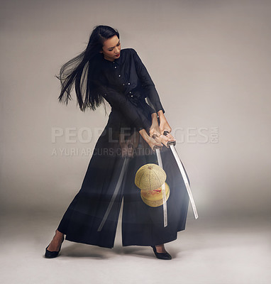 Buy stock photo Ninja, sword and a woman cutting a melon in studio on a gray background for warrior training. Samurai, fantasy and cosplay with an asian female using a sharp weapon to slice fruit for martial arts