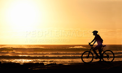 Buy stock photo A silhouette of a female cyclist on the beach at sunset