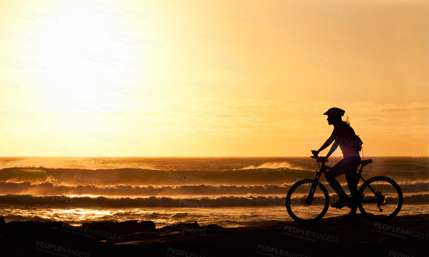 Buy stock photo A silhouette of a female cyclist on the beach at sunset