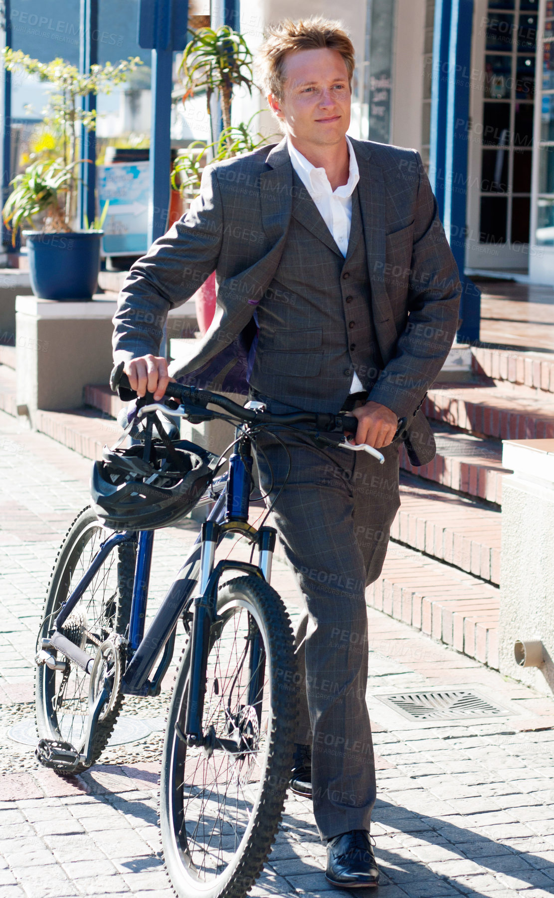 Buy stock photo Shot of an attractive young man pushing his bicycle on the way to work