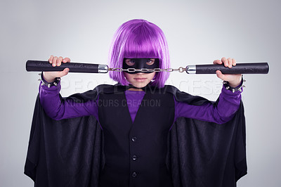 Buy stock photo Girl, halloween and superhero vigilante with nunchucks for fighting against grey studio background. Portrait of isolated little girl playing super hero with martial art karate weapon and purple hair