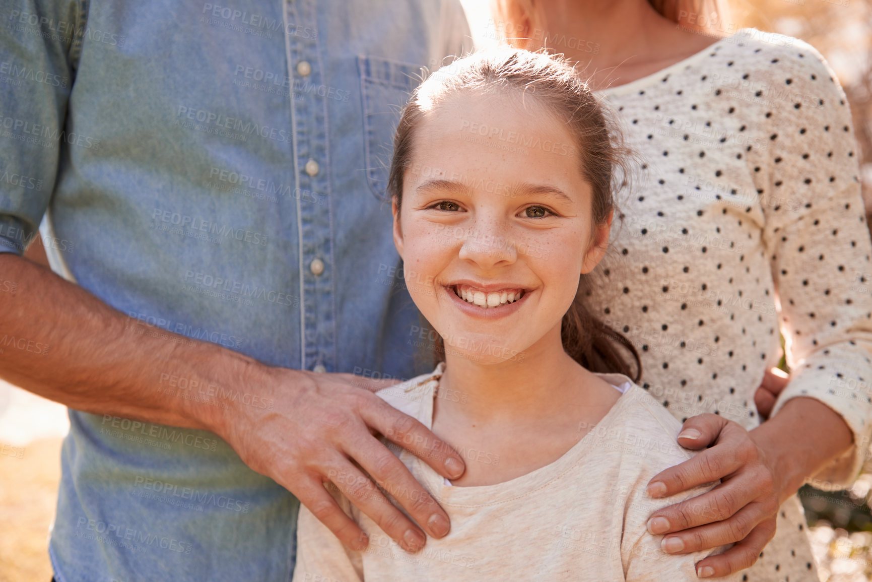 Buy stock photo A cropped portrait of a happy young girl standing outdoors with her parents