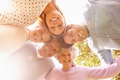 Buy stock photo A low angle portrait of a happy family standing in a huddle