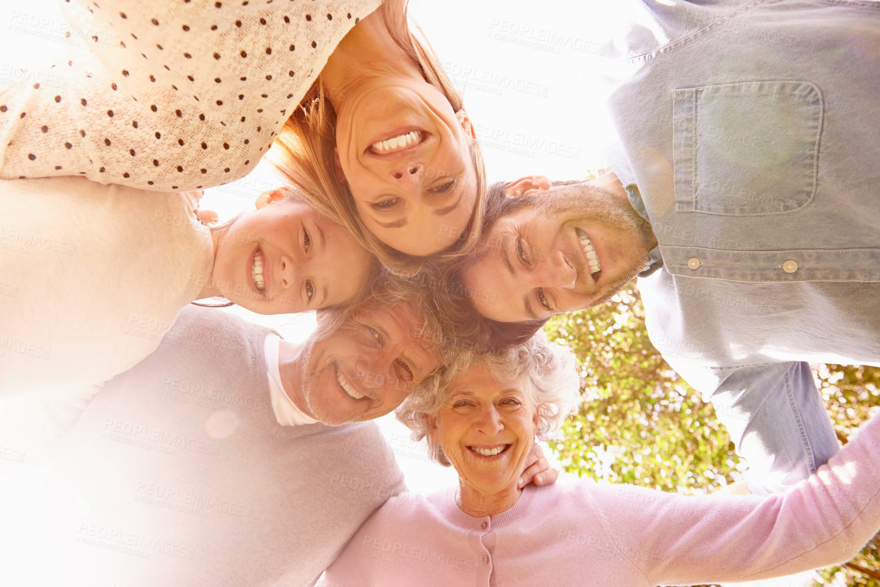 Buy stock photo A low angle portrait of a happy family standing in a huddle