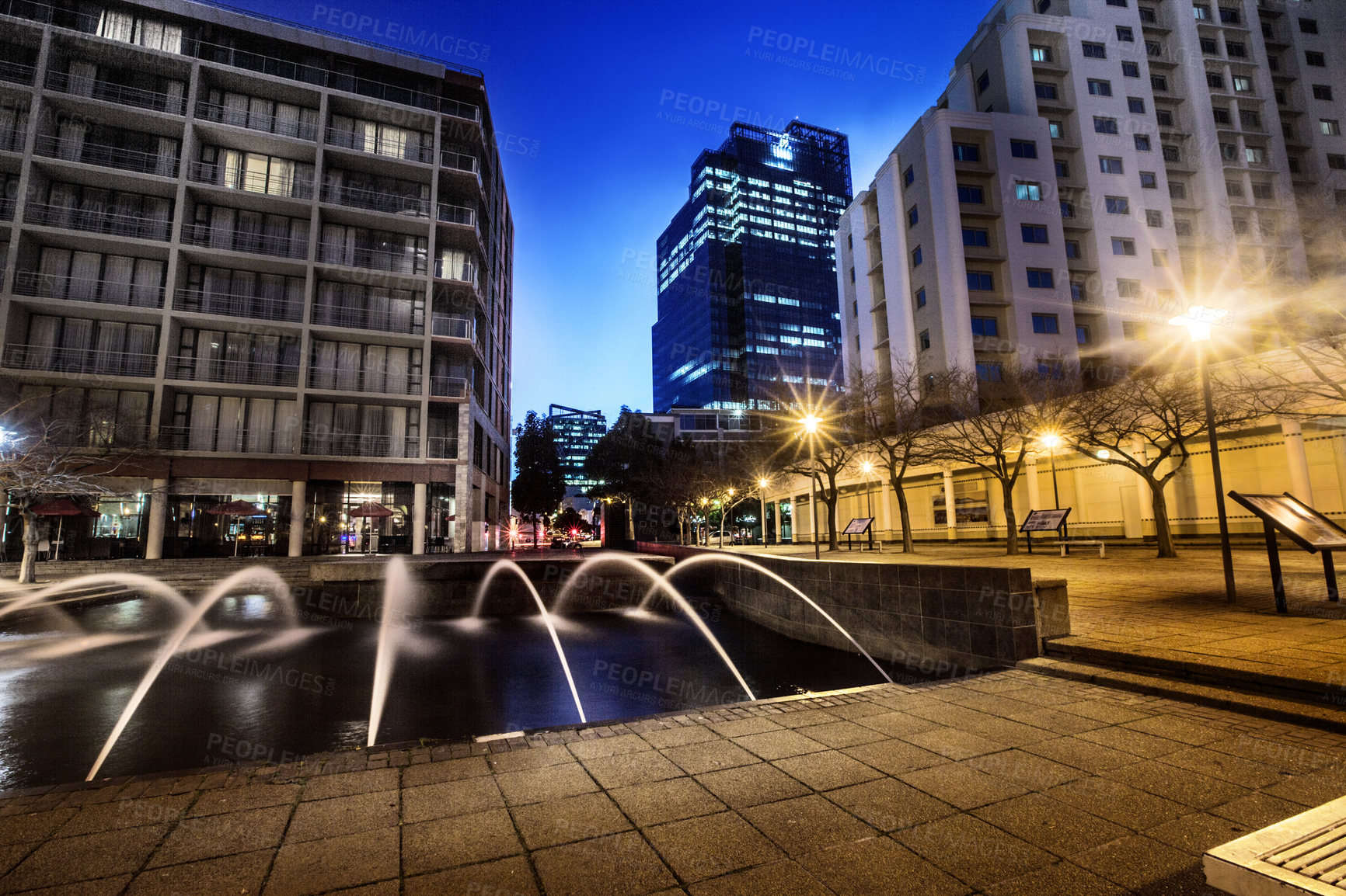 Buy stock photo Night, cityscape and urban buildings at dark with lights in Cape Town outdoor with no people. Street, lighting and city infrastructure with fountain and skyline at evening outdoors with a road