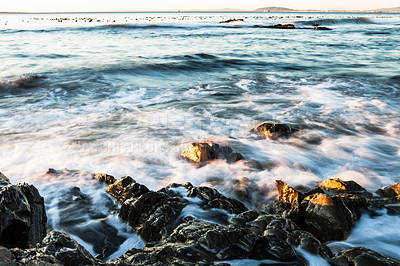 Buy stock photo Rock, ocean and water with waves at beach for environment, landscape and blue sky. Calm, summer and natural with morning seascape on horizon for tropical coastline, marine and nature long exposure