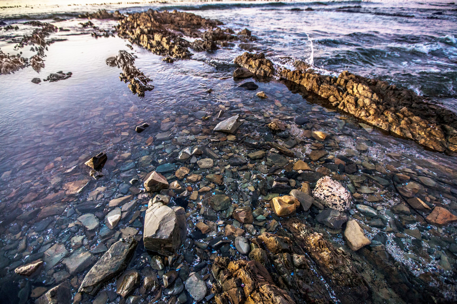 Buy stock photo Nature, environment and ocean with rock at beach for sunset, calm and seascape. Natural scenery, waves and stone on coastline in outdoors for morning sunrise, marine water and sea landscape