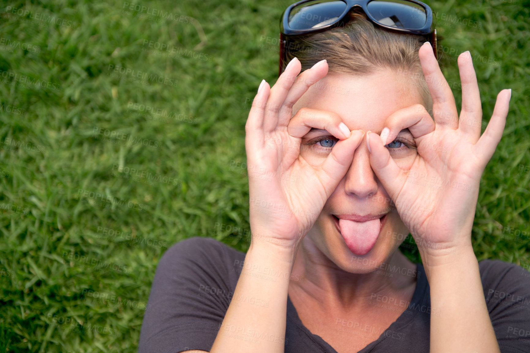 Buy stock photo Portrait, hand glasses and woman with tongue out for funny face, goofy or silly in outdoor garden. Top view, comic and female person joking for humor, finger shape gesture and playful mood in park