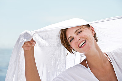 Buy stock photo A beautiful young woman holding a white sarong that's blowing in the wind