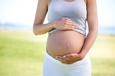 Buy stock photo Cropped shot of a pregnant woman dressed in workout clothing outdoors