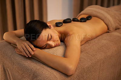 Buy stock photo Bed, woman and massage with stone at spa for stress relief, organic body health and detox. Towel, relax and zen female person with hot rock for wellness, self care and spiritual healing at resort
