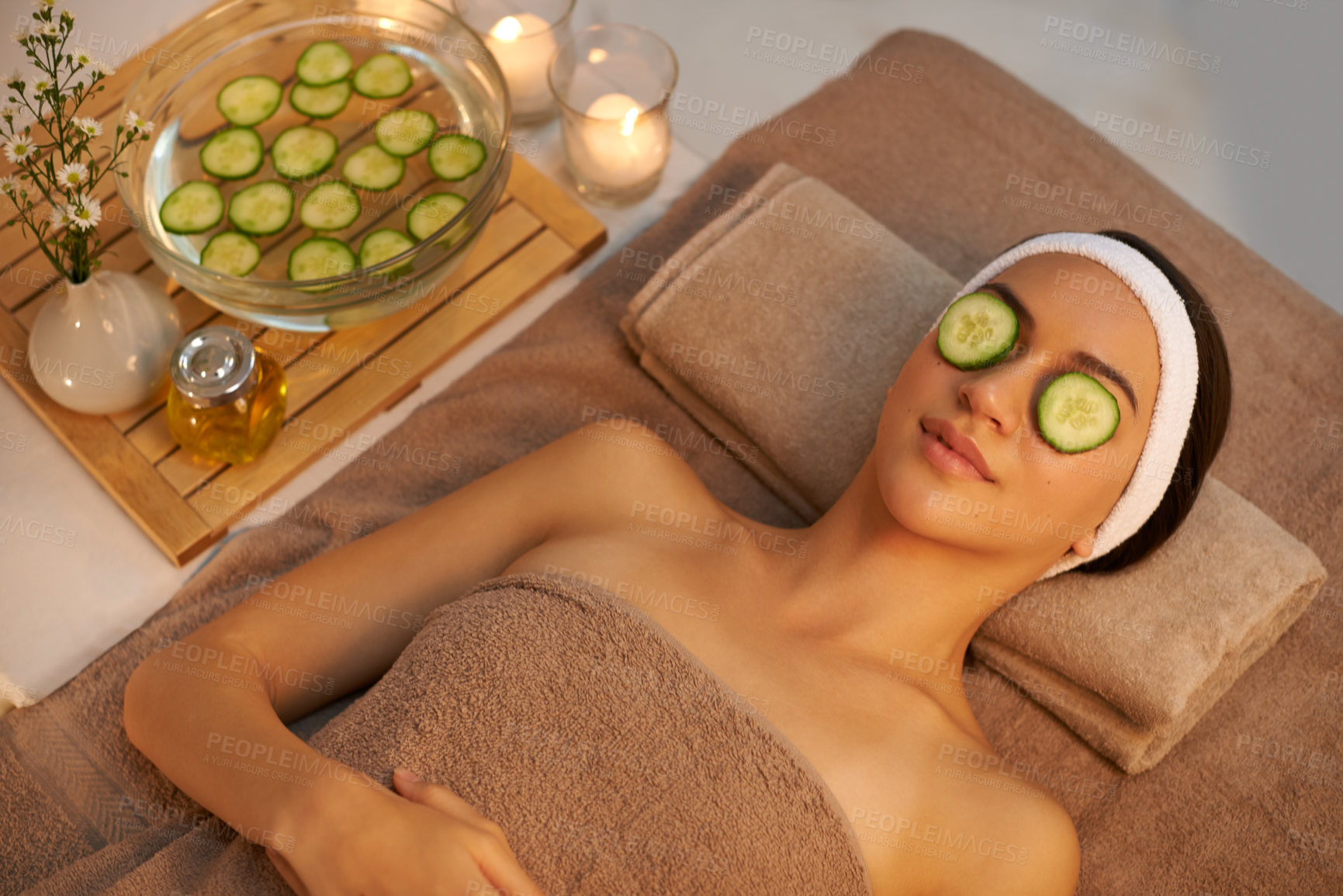 Buy stock photo A beautiful young woman lying on a massage table at the spa with cucumer over her eyes