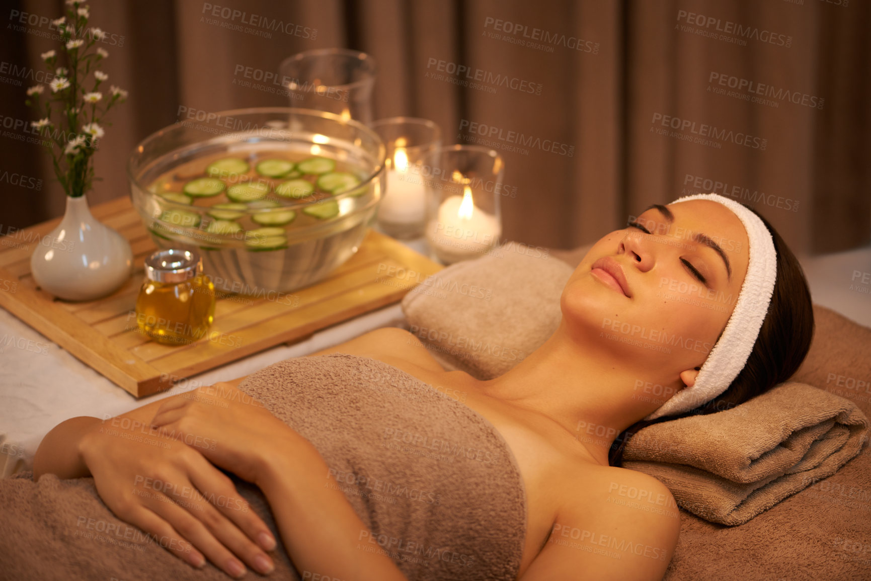 Buy stock photo Sleeping, relax and woman at massage table in spa with cucumber for peace, calm or skincare. Body, salon and person resting for aromatherapy with candles for natural beauty or health with eyes closed